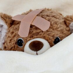 Ein kranker Teddy liegt im Bett.