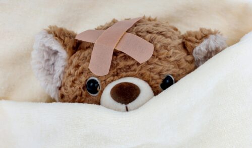 Ein kranker Teddy liegt im Bett.