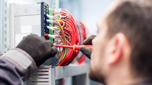 Ein Elektriker arbeitet an einem Schaltschrank mit vielen Kabeln