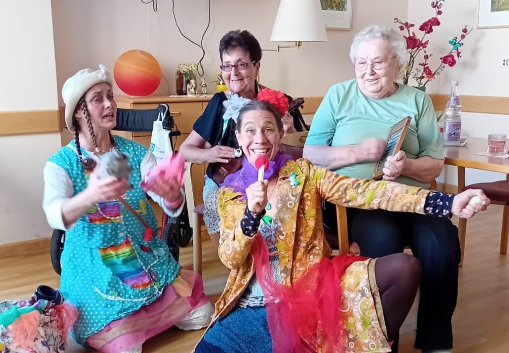 Zwei Clowns machen Musik mit zwei Heimbewohnerinnen.