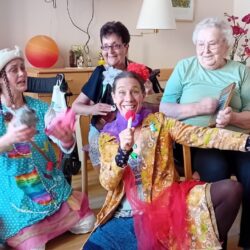 Zwei Clowns machen Musik mit zwei Heimbewohnerinnen.