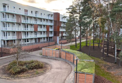 Ein modernisierter Häuserblock steht neben einer Baumgruppe