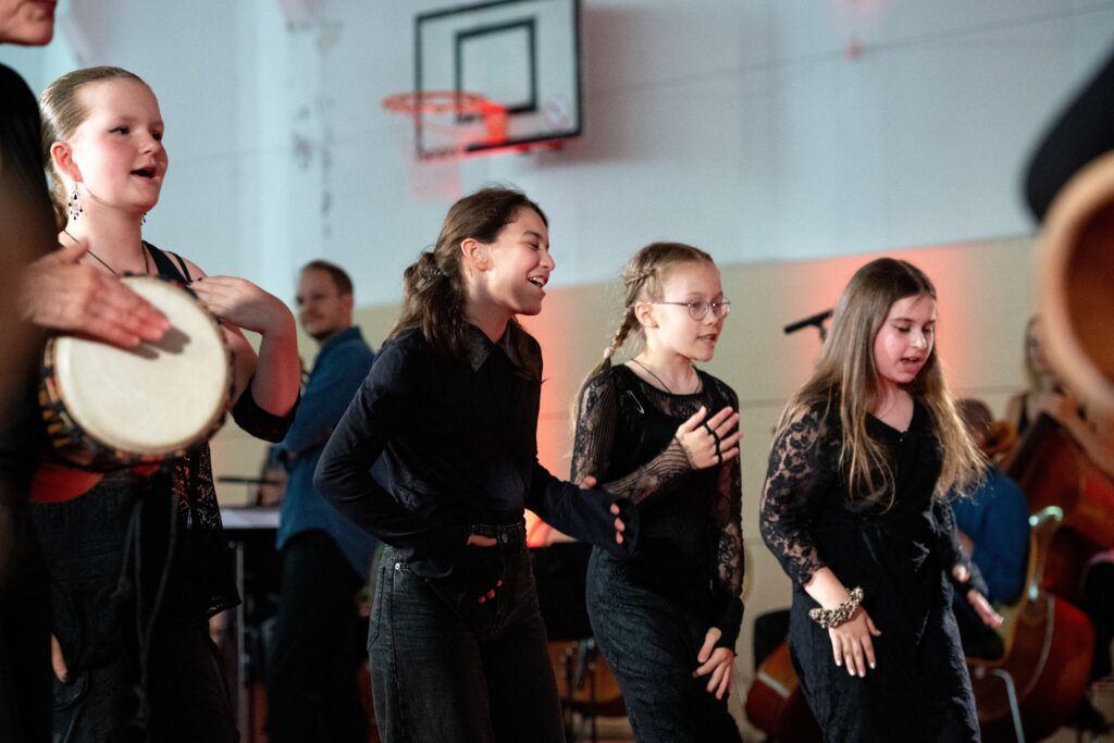 Gruppe von Schülerinnen, die gemeinsam Musik machen und singen.