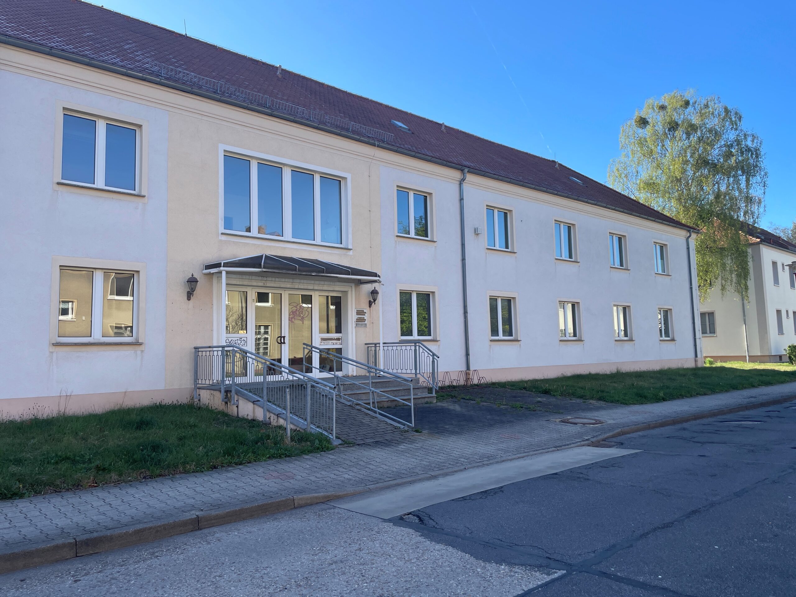 Außenansicht eines zweigeschossigen Funktionsgebäudes mit heller Fassade und einem behindertengerechten Eingang.