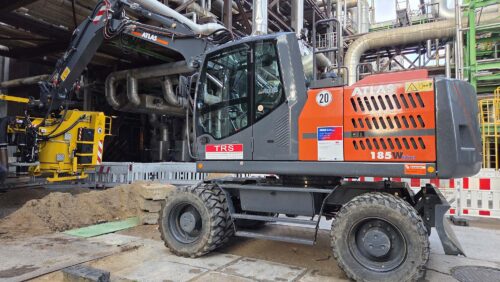 Ein großer Bagger mit Anbausauger steht auf einer Baustelle